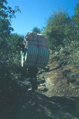 Träger mit einem Berg von Matrazen auf dem Rücken