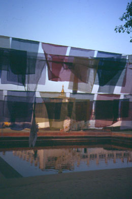 im Teich unter Gebetsfahnen spiegelt sich ein Tempel